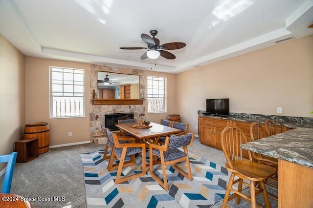 dining area featuring a raised ceiling, light colored carpet, and plenty of natural light