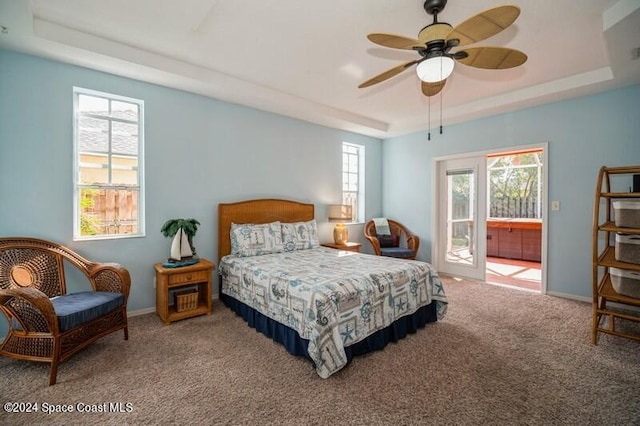 carpeted bedroom featuring ceiling fan, a tray ceiling, and multiple windows