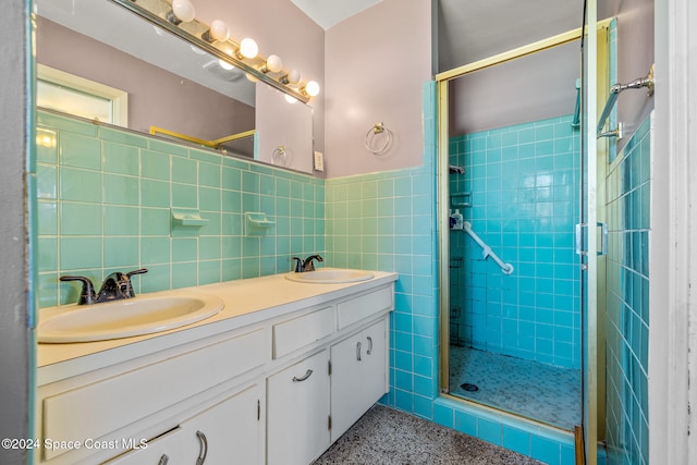 bathroom with vanity, a shower with door, and tile walls