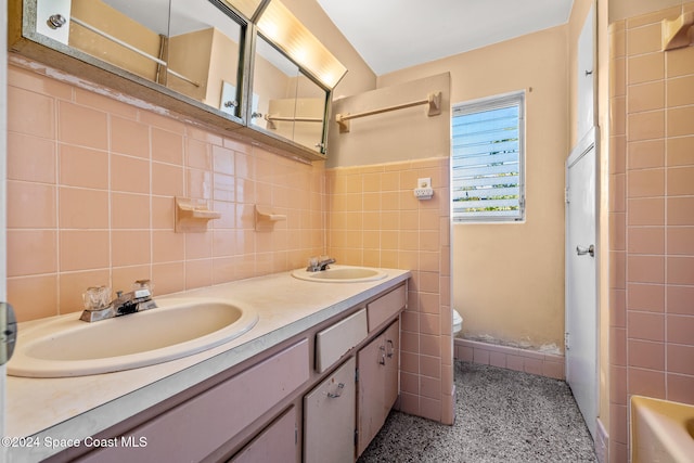 bathroom with a shower, vanity, tile walls, and toilet