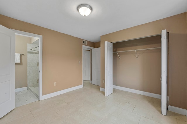 unfurnished bedroom featuring a closet, ensuite bathroom, and light tile patterned floors