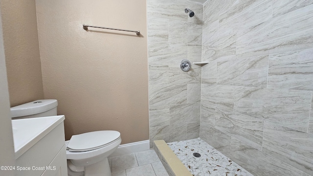 bathroom featuring vanity, tile patterned flooring, toilet, and tiled shower