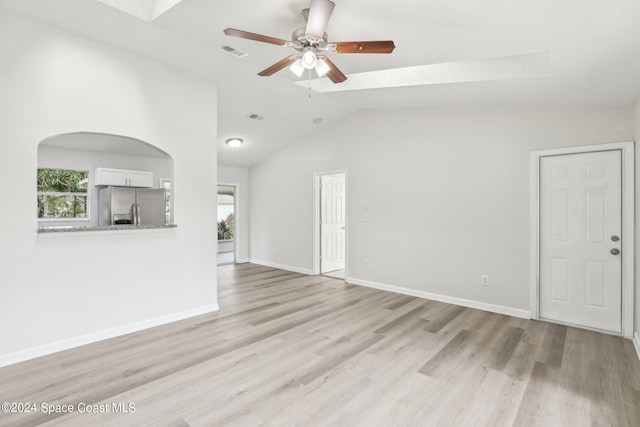 empty room with light hardwood / wood-style flooring, lofted ceiling with skylight, and ceiling fan