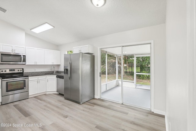 kitchen featuring appliances with stainless steel finishes, sink, light wood-type flooring, white cabinetry, and lofted ceiling