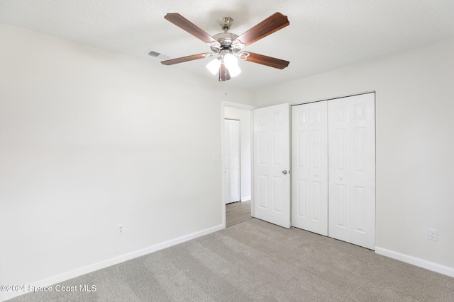 unfurnished bedroom featuring light carpet, a textured ceiling, and ceiling fan