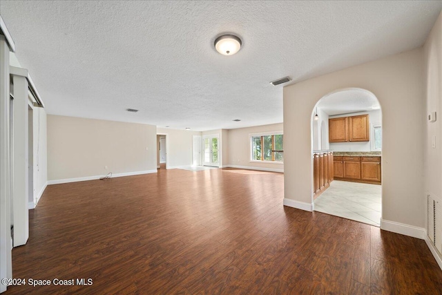 unfurnished living room with a textured ceiling and light hardwood / wood-style flooring