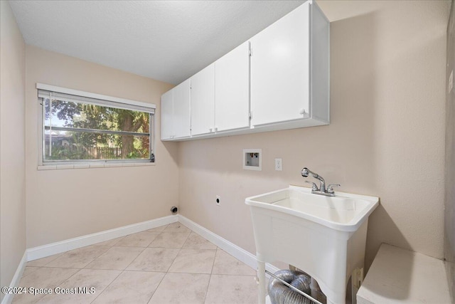 laundry area featuring sink, hookup for a washing machine, light tile patterned floors, electric dryer hookup, and cabinets