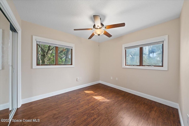 unfurnished bedroom with ceiling fan, a textured ceiling, dark hardwood / wood-style floors, and a closet