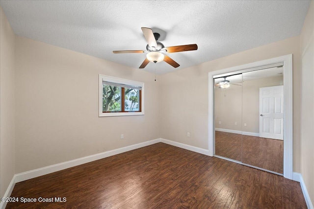 unfurnished bedroom featuring ceiling fan, dark wood-type flooring, a textured ceiling, and a closet