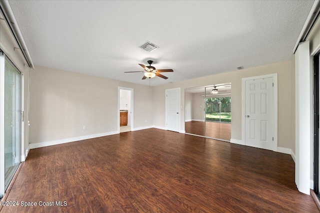 unfurnished living room featuring a textured ceiling, dark wood-type flooring, and ceiling fan