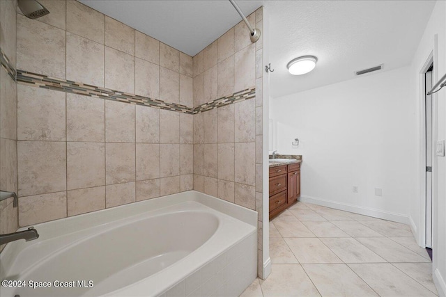 bathroom featuring a textured ceiling, tile patterned flooring, tiled shower / bath, and vanity