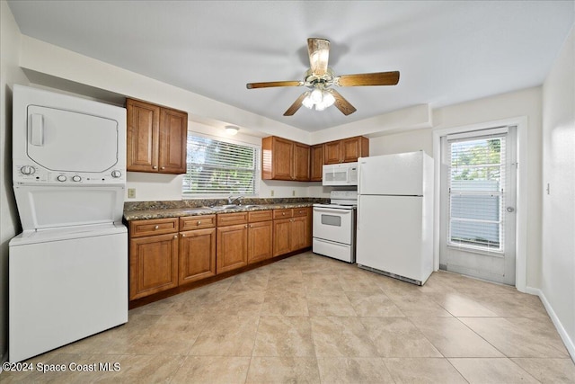 kitchen featuring stacked washer / drying machine, plenty of natural light, sink, and white appliances