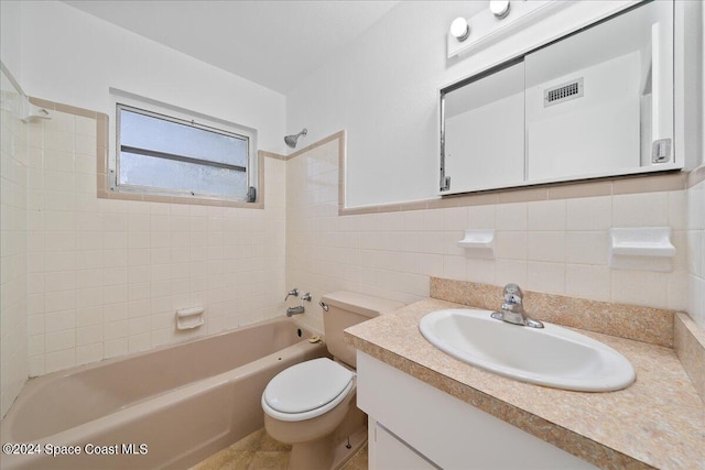 full bathroom featuring toilet, tiled shower / bath combo, tile walls, and vanity