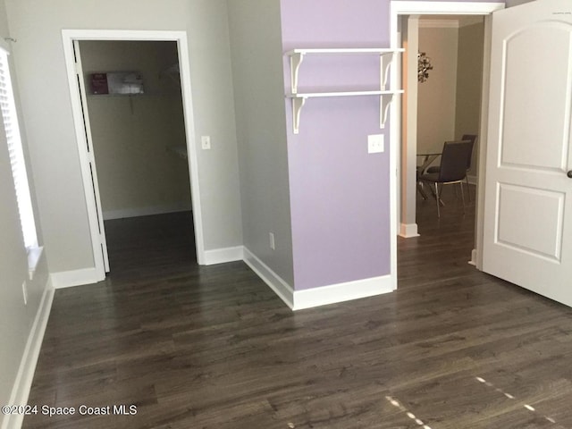 unfurnished bedroom featuring a spacious closet, a closet, and dark hardwood / wood-style floors