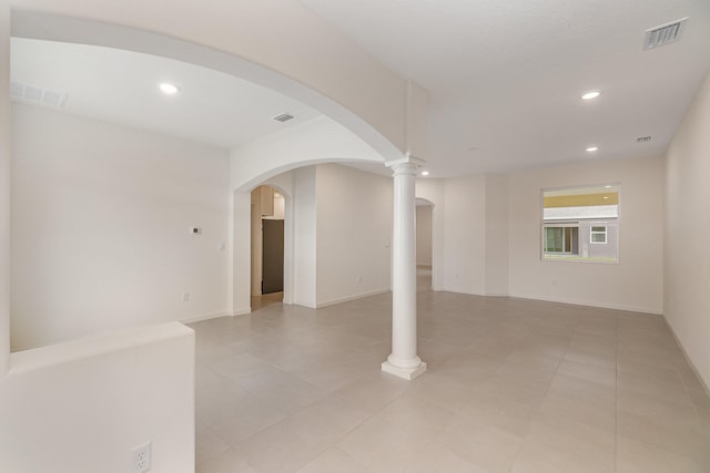 spare room featuring ornate columns and light tile patterned floors