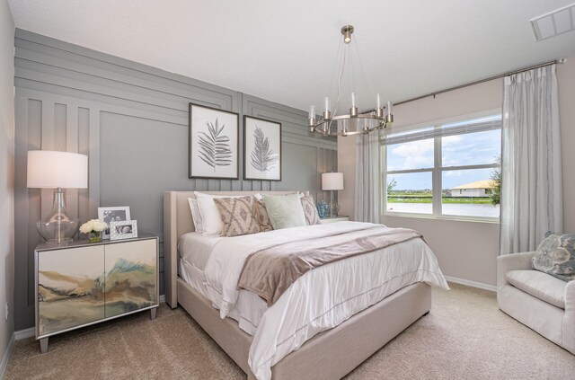 carpeted bedroom featuring an inviting chandelier, wooden walls, and a water view