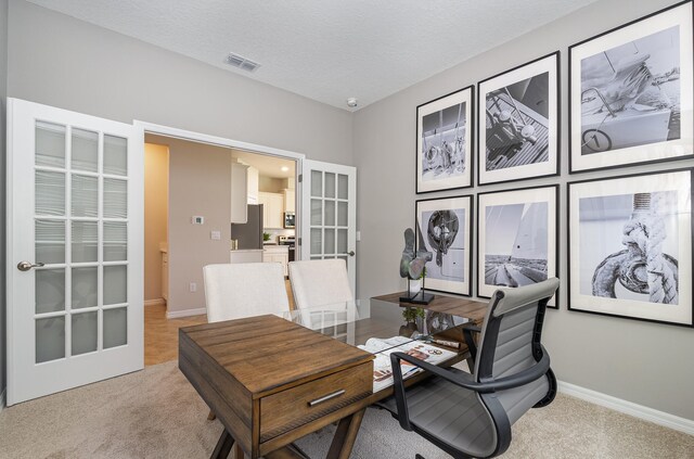 home office featuring french doors, a textured ceiling, and light colored carpet