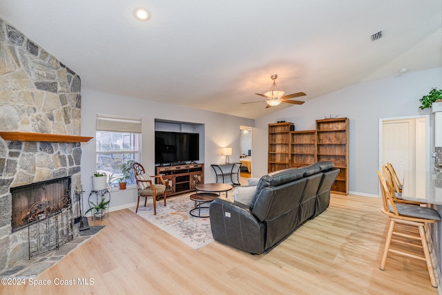 living room with vaulted ceiling, a fireplace, light hardwood / wood-style floors, and ceiling fan