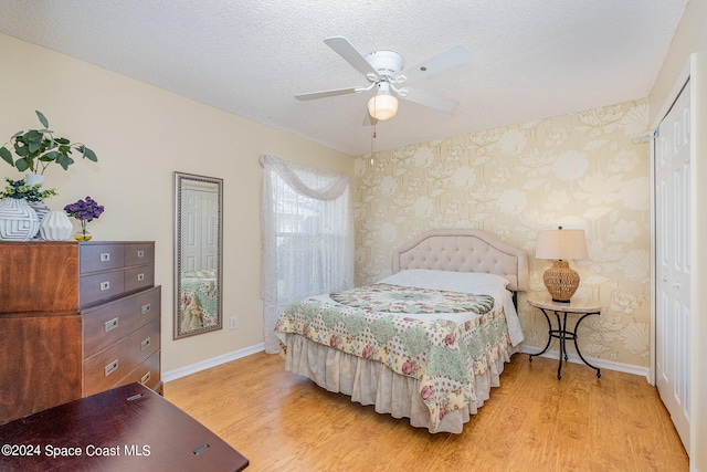 bedroom with light hardwood / wood-style flooring, a textured ceiling, a closet, and ceiling fan