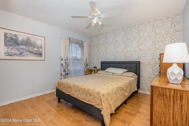 bedroom with a textured ceiling, light wood-type flooring, and ceiling fan