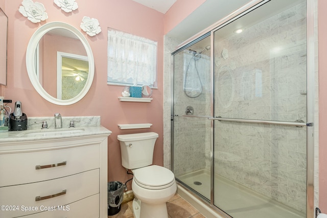 bathroom with vanity, toilet, a shower with shower door, and tile patterned flooring