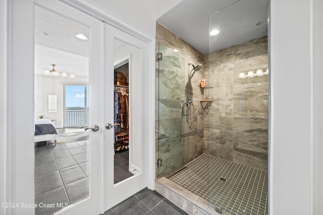 bathroom with tile patterned floors, ceiling fan, a shower with shower door, and french doors