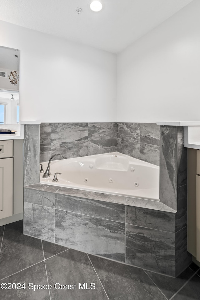 bathroom featuring tile patterned flooring, vanity, and tiled tub