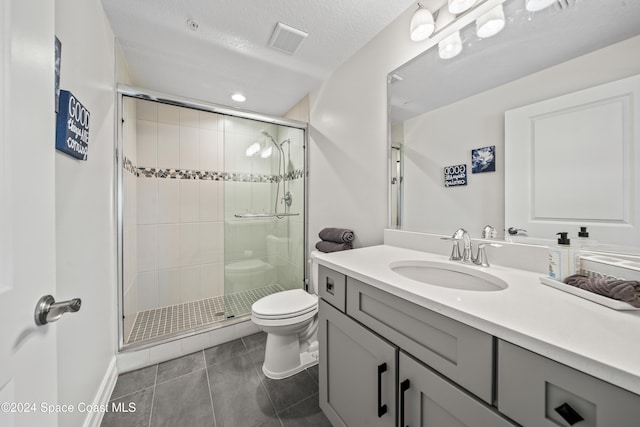 bathroom with tile patterned floors, vanity, a textured ceiling, a shower with door, and toilet