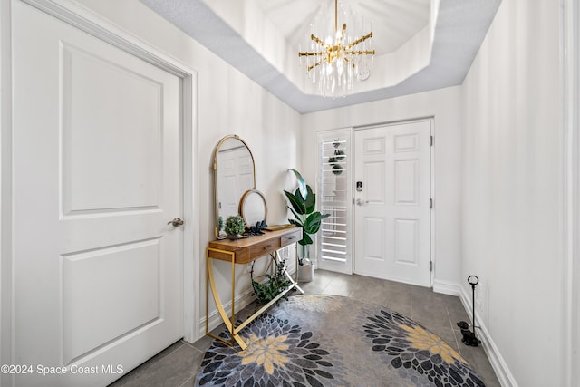 tiled foyer with a chandelier and a tray ceiling