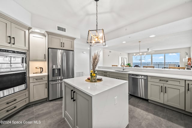 kitchen featuring decorative light fixtures, a center island, stainless steel appliances, and gray cabinetry