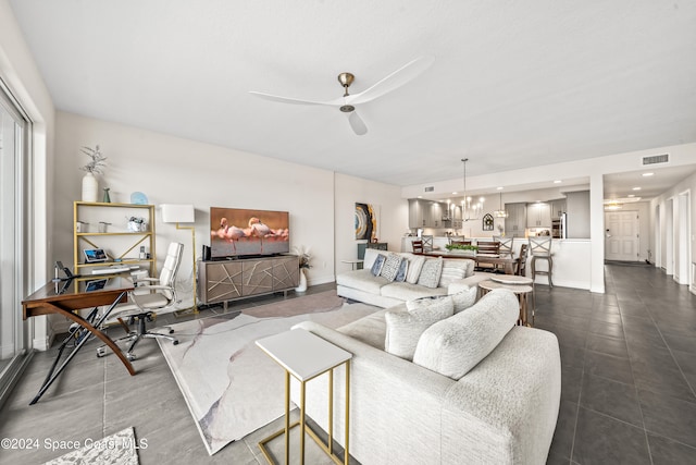 tiled living room with ceiling fan with notable chandelier