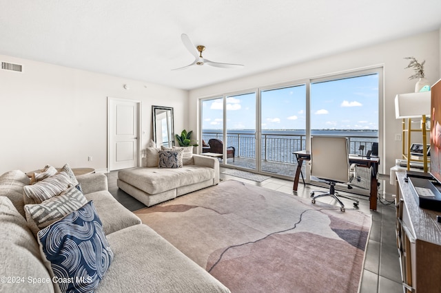 tiled living room with ceiling fan and a water view