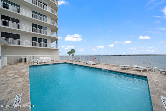 view of pool featuring a water view and a patio area