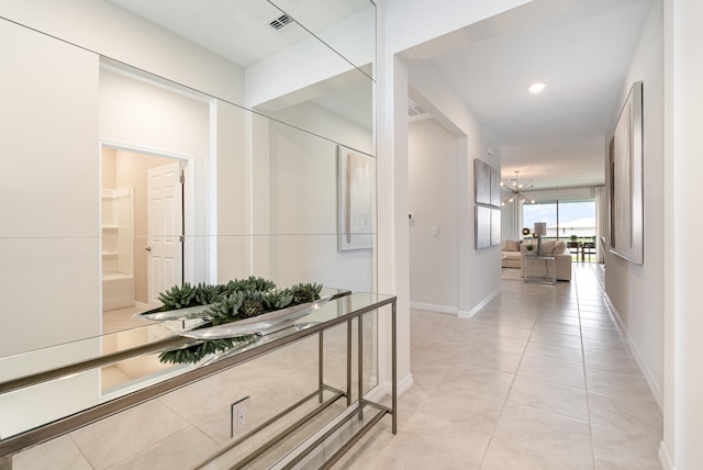 hallway with a chandelier and light tile patterned flooring