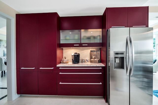 kitchen featuring light stone countertops, light tile patterned floors, and stainless steel refrigerator with ice dispenser