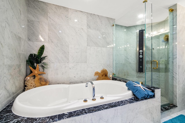 bathroom with tile walls and shower with separate bathtub