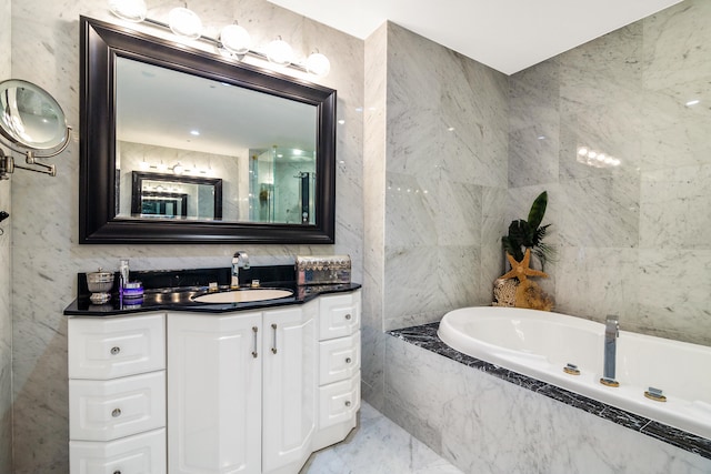 bathroom with vanity, a relaxing tiled tub, and tile walls