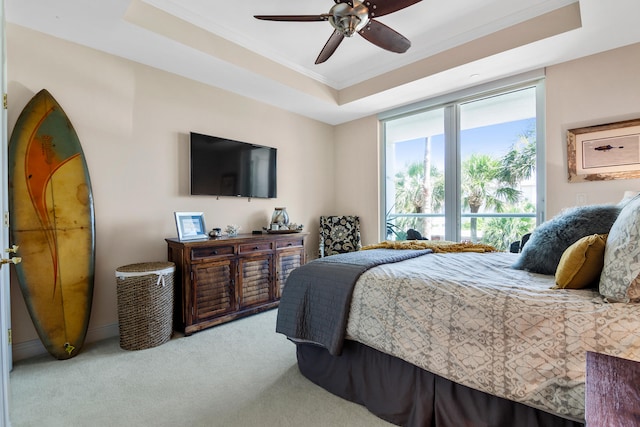 carpeted bedroom with ceiling fan, a raised ceiling, and crown molding