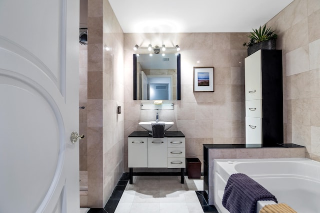 bathroom featuring vanity, tile walls, tile patterned flooring, and a bathing tub