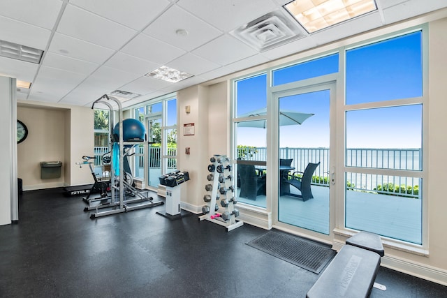 gym with a paneled ceiling and expansive windows