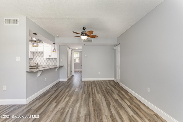 unfurnished living room featuring sink, dark wood-type flooring, a textured ceiling, and ceiling fan