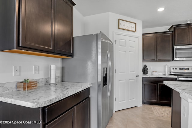 kitchen with dark brown cabinets, light tile patterned floors, and stainless steel appliances