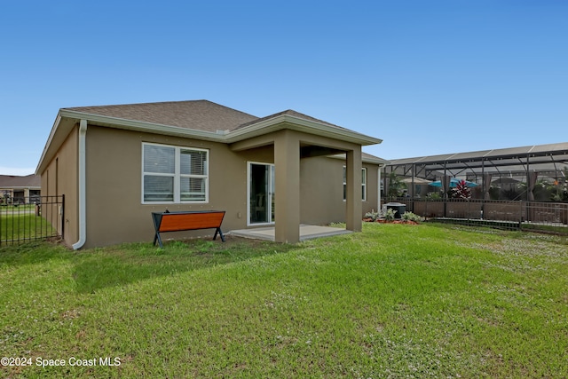 rear view of property with glass enclosure, a lawn, and a patio