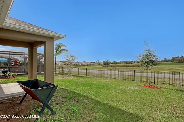 view of yard with glass enclosure and a rural view