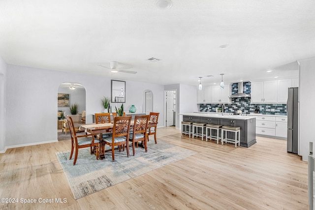 dining space featuring sink, light wood-type flooring, and ceiling fan