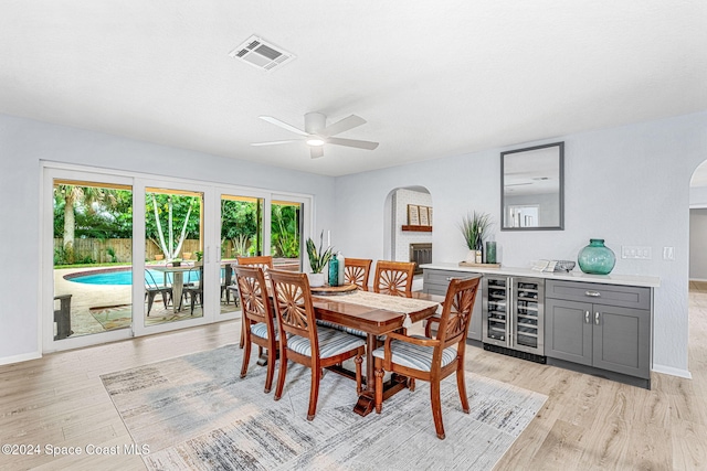 dining space featuring light hardwood / wood-style floors, ceiling fan, a healthy amount of sunlight, and beverage cooler