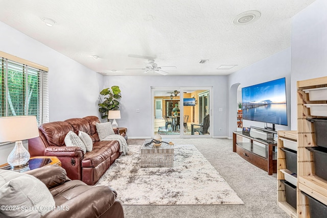 carpeted living room with ceiling fan and a textured ceiling