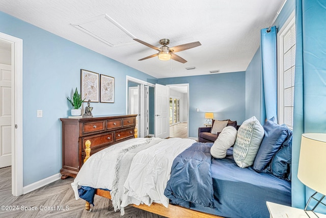 bedroom with ceiling fan, light parquet flooring, and a textured ceiling