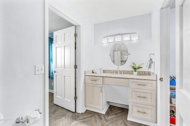 bathroom with parquet flooring, vanity, and a textured ceiling