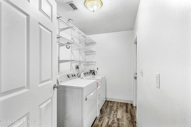 laundry area with a textured ceiling, washing machine and clothes dryer, and hardwood / wood-style floors